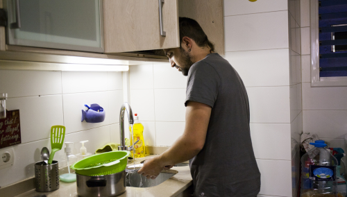 A young man washing upin his kitchen